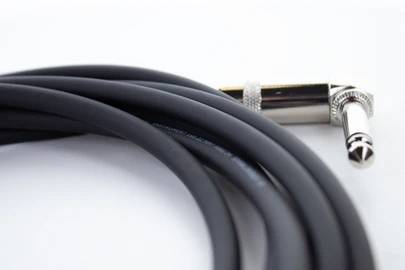 Ein schwarzes Audiokabel mit einem rechtwinkligen Klinkenstecker, aufgerollt und bereit zur Nutzung.