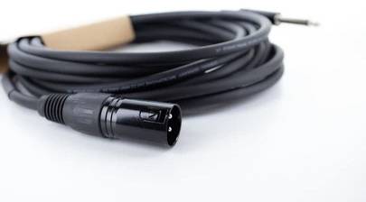 Ein zusammengerolltes Audiokabel mit XLR- und Klinkenstecker, auf einem weißen Hintergrund liegend.