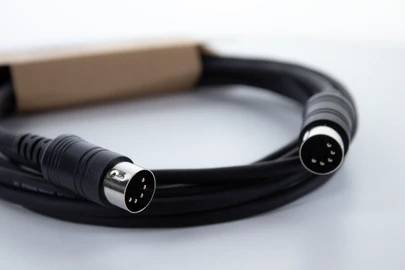 Schwarzes Audiokabel mit zwei 5-poligen Anschlusssteckern, auf einem Tisch liegend, für die Verbindung elektronischer Geräte.