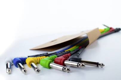 Buntes Set von Audiokabeln mit verschiedenen Steckern, nebeneinander liegend.