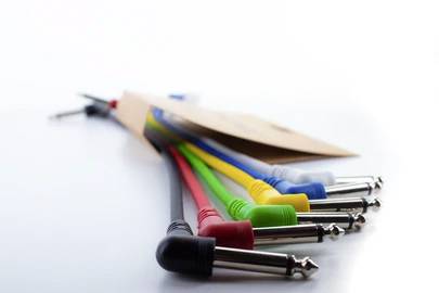 Mehrere bunte Audiokabel mit Klinkensteckern liegen nebeneinander auf einem weißen Hintergrund.