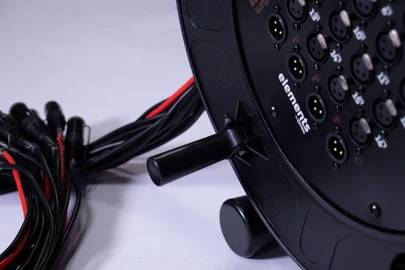 Nahaufnahme eines schwarzen Kabeltrommel-Adapters mit mehreren XLR-Anschlüssen und Kabeln.