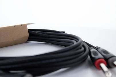 Schwarzes Audiokabel mit zwei Steckern, einer rot und einer schwarz markiert, auf weißem Hintergrund. Kabel teilweise in Papierschlaufe.