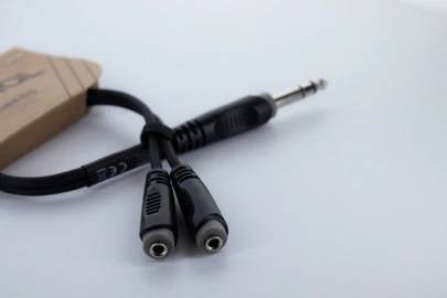 Ein Audio-Adapterkabel mit einem 6,3-mm-Stereo-Klinkenstecker auf zwei 3,5-mm-Buchsen. Rechte Verpackungsecke sichtbar.