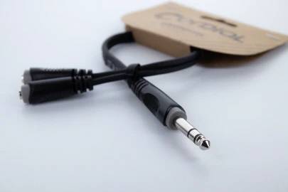 Audio-Klinkenkabel mit Y-Splitter, einer schwarzen Leitung und silbernem Stecker, auf weißem Hintergrund. Verpackung im Hintergrund.