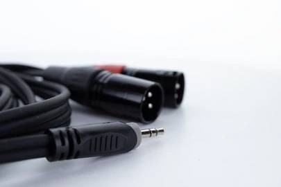 Schwarz-rotes Audiokabel mit XLR- und Klinkenstecker, auf einer weißen Oberfläche liegend. Nutzt man zur Tonübertragung.