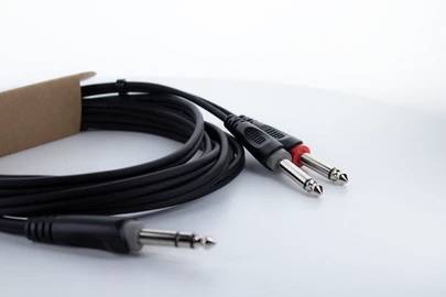 Stereo-Audiokabel: Ein Kabel mit zwei 6,3 mm-Klinkensteckern und einem 3,5 mm-Klinkenstecker, auf weißem Hintergrund.