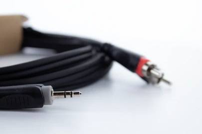 Ein schwarzes Audiokabel mit einem 3,5-mm-Stecker auf der einen und zwei Cinch-Steckern auf der anderen Seite auf weißem Hintergrund.