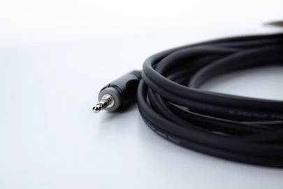 Ein schwarzes Audiokabel mit einem silbernen 3,5-mm-Klinkenstecker liegt auf einem weißen Hintergrund.