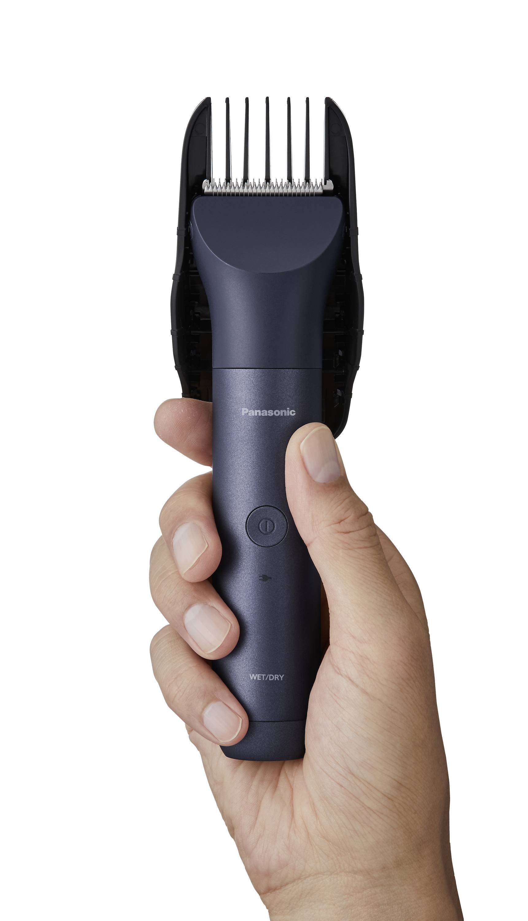 Ein elektrischer Haarschneider wird in der Hand gehalten. Das Gerät ist dunkelgrau mit silbernen Klingen und hat eine ergonomische Form.