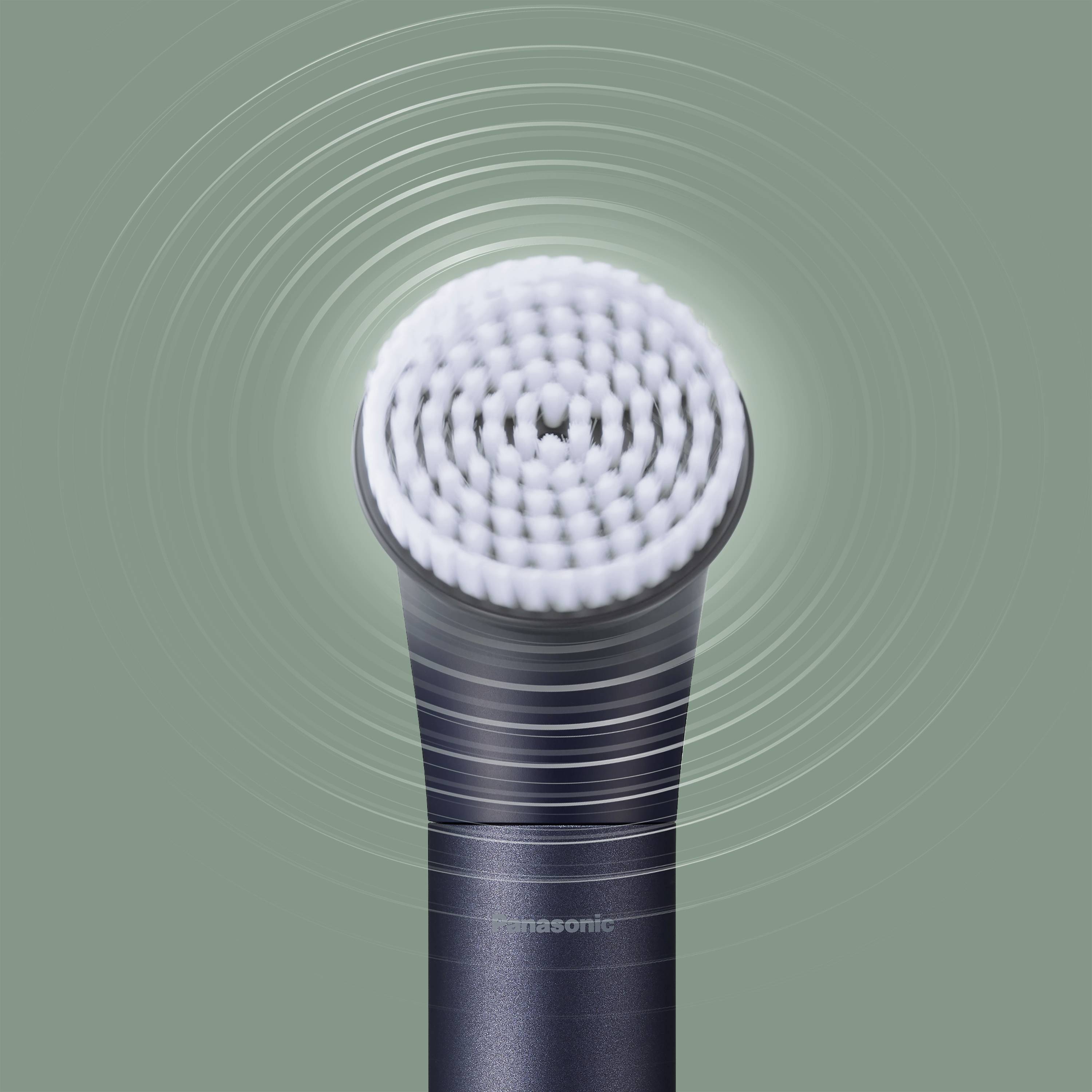 Elektrische Zahnbürste mit kreisförmigem Bürstenkopf, der Vibrationen darstellt, vor grünem Hintergrund.