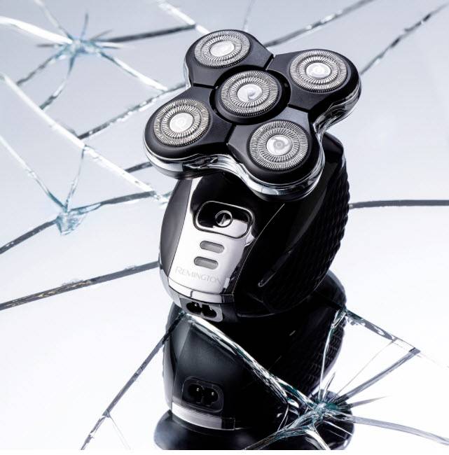 Elektrorasierer mit fünf Scherköpfen auf gebrochenem Spiegel. Design balanciert Technik und Eleganz. Dynamisches, modernes Image.