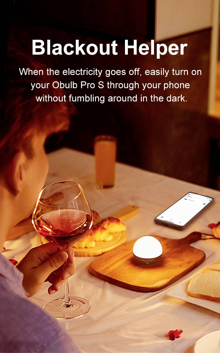 Eine Person sitzt bei Kerzenlicht mit einem Glas Wein in der Hand. Ein Handy liegt mit eingeschaltetem Bildschirm daneben.