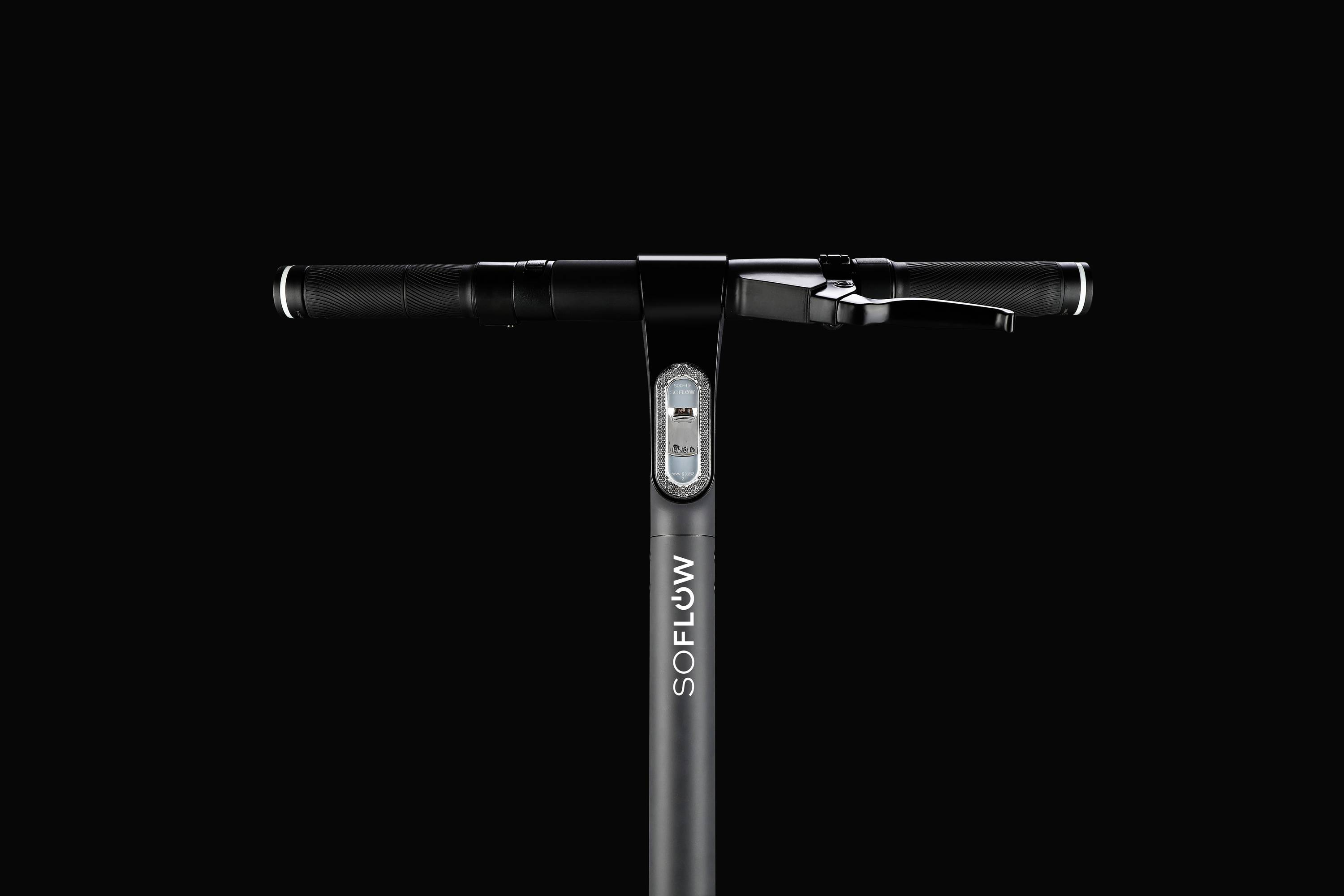 Elektroroller-Lenker mit Display in der Mitte, Firmenlogo 'SOFLOW' auf der Stange. Design in Schwarz auf schwarzem Hintergrund.