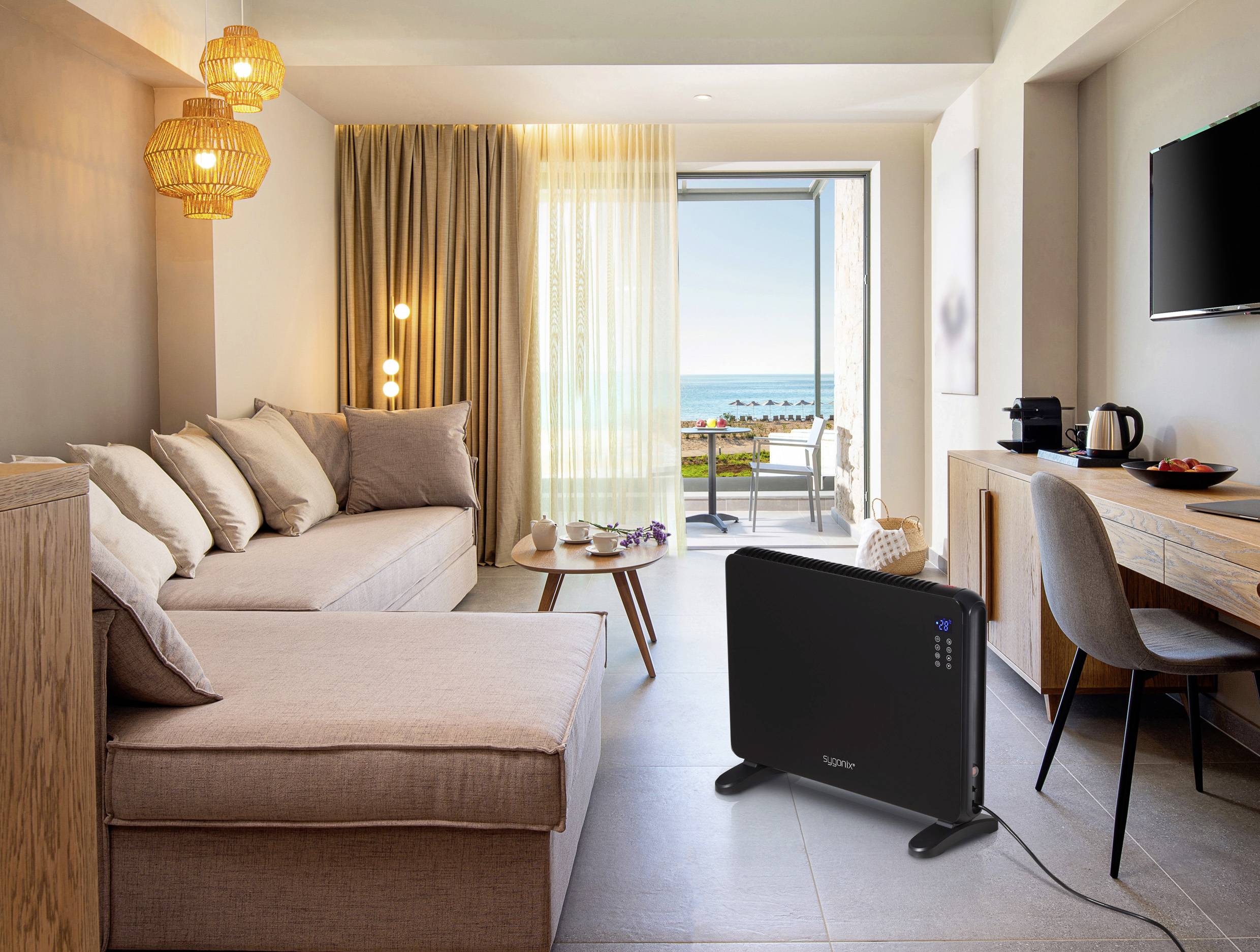 Ein modernes Wohnzimmer mit Sofa, Couchtisch und großem Fenster mit Meeresblick. Ein Heizgerät steht auf dem Boden.