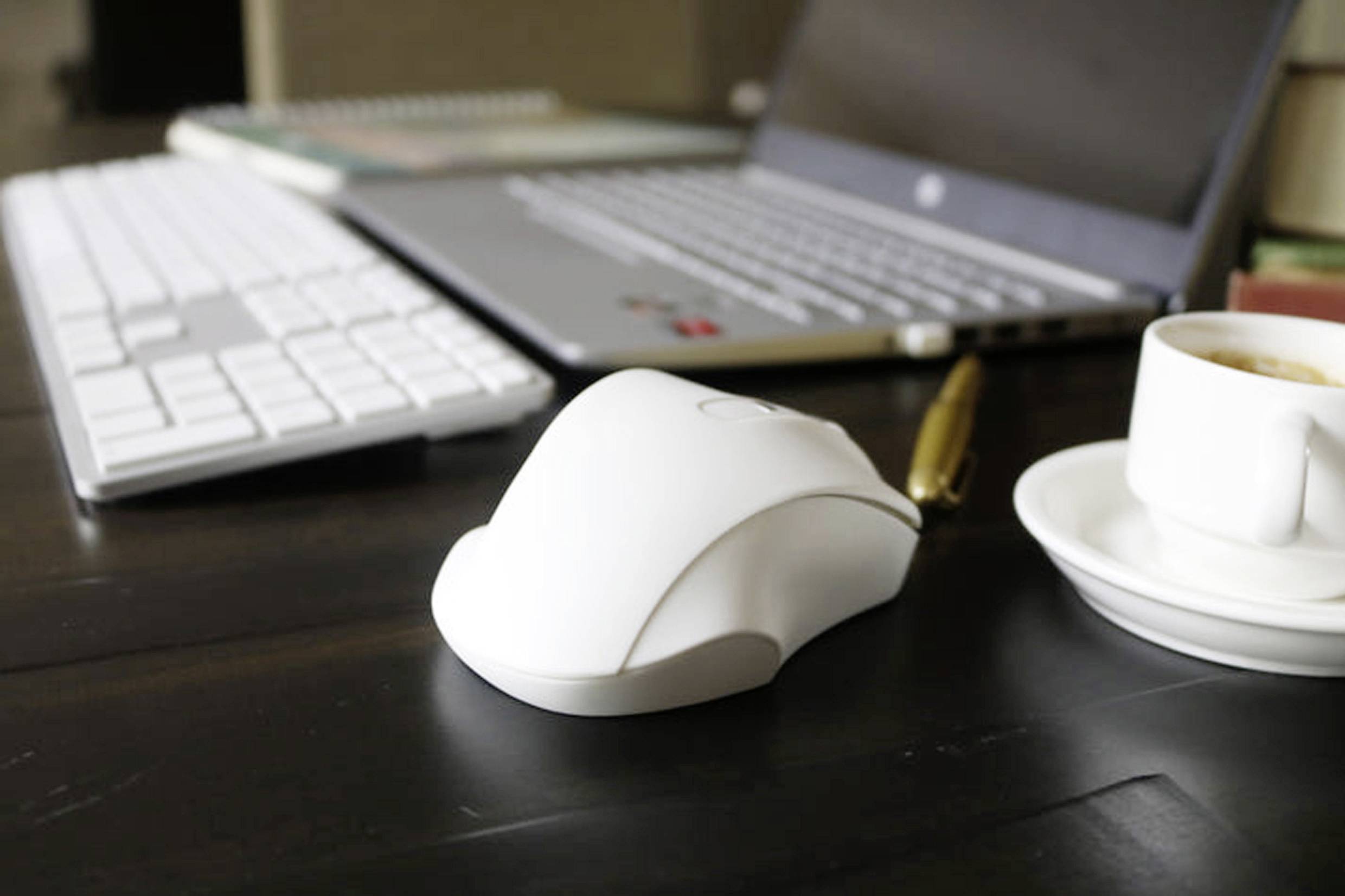 Laptop auf einem Holztisch mit einer Computermaus, Tastatur und einer Kaffeetasse. Büroeinrichtung für produktives Arbeiten.