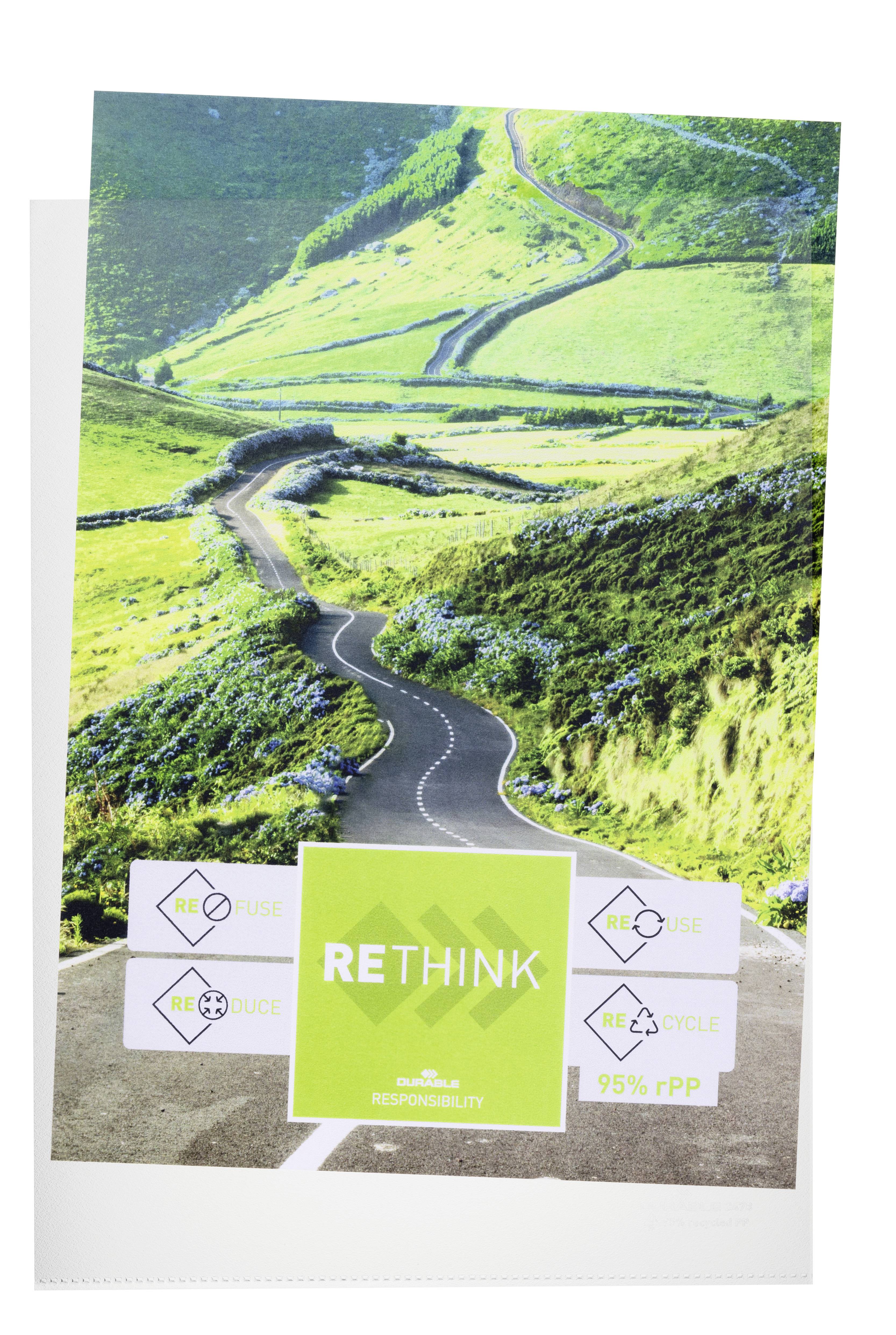 Eine kurvige Straße schlängelt sich durch grüne Hügel. Im Vordergrund ein Schild mit der Aufschrift 'RETHINK', umgeben von Recycling-Symbolen.