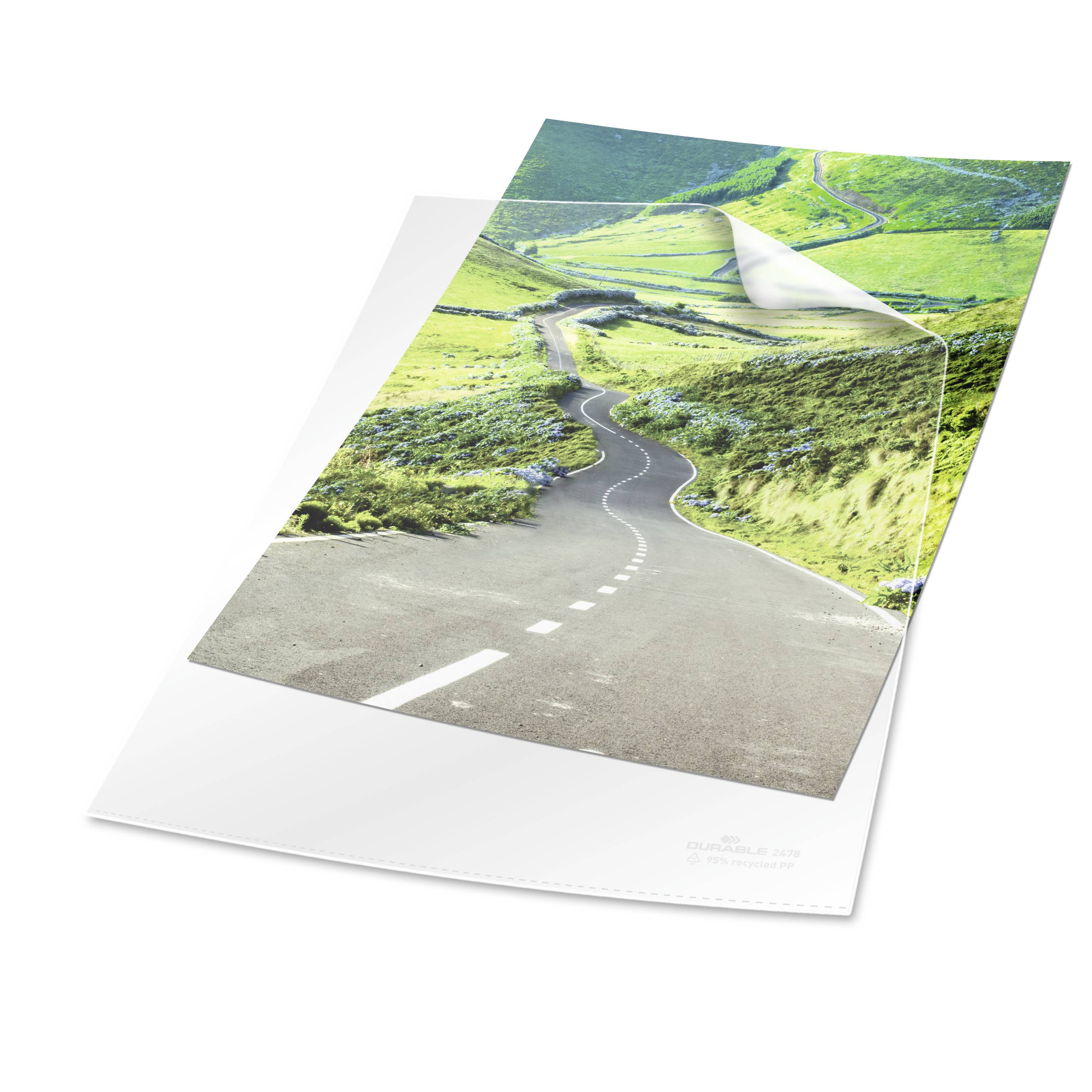 Ein Bild einer Landstraße, die durch eine grüne Hügellandschaft führt. Der Himmel ist klar und blau, was eine ruhige Szenerie vermittelt.