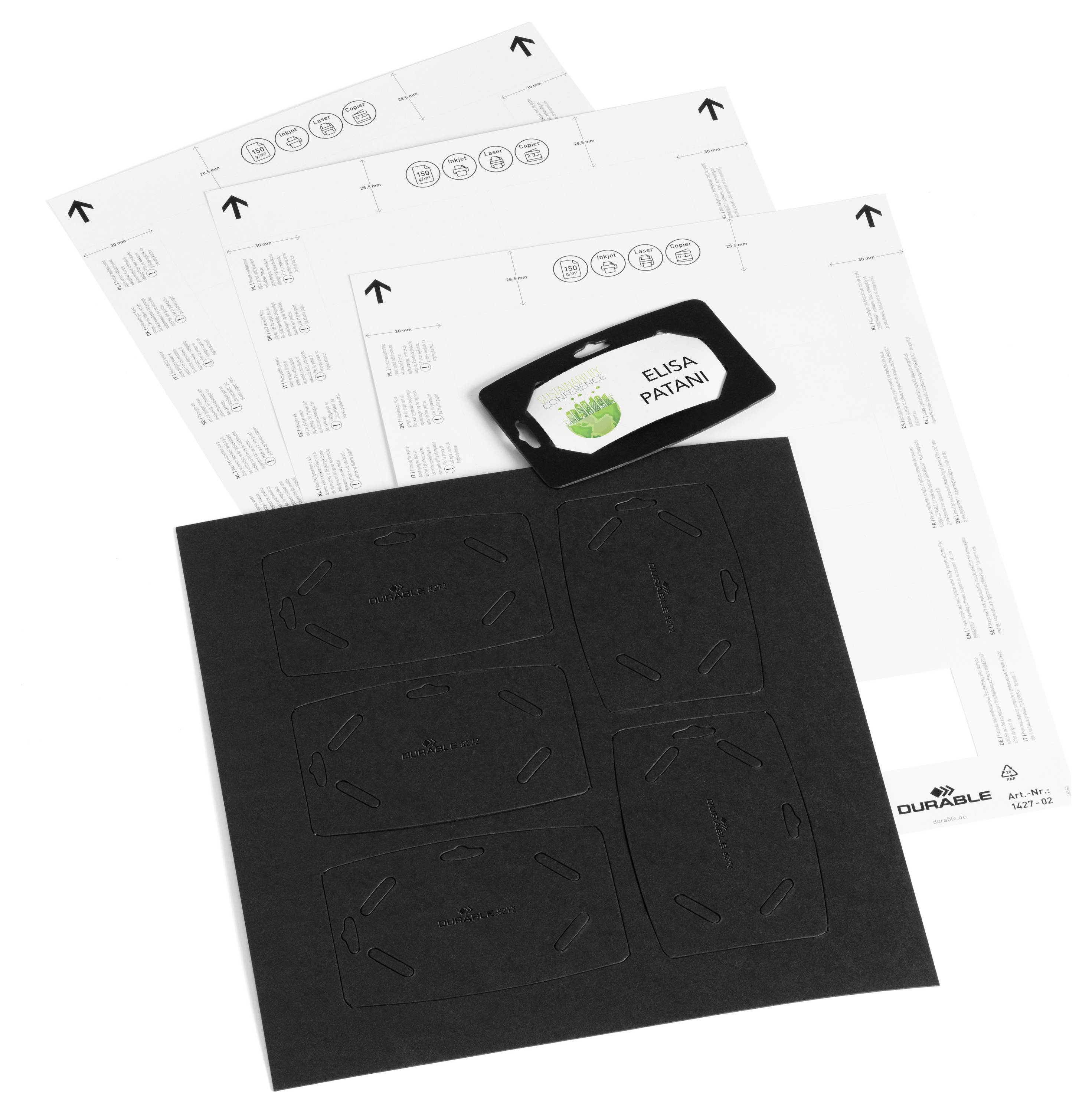 Ein Namensschild mit dem Text 'ELISA PATANI' auf schwarzem Hintergrund liegt auf gestanzten Etikettenbögen. Weitere Bögen umgeben es.