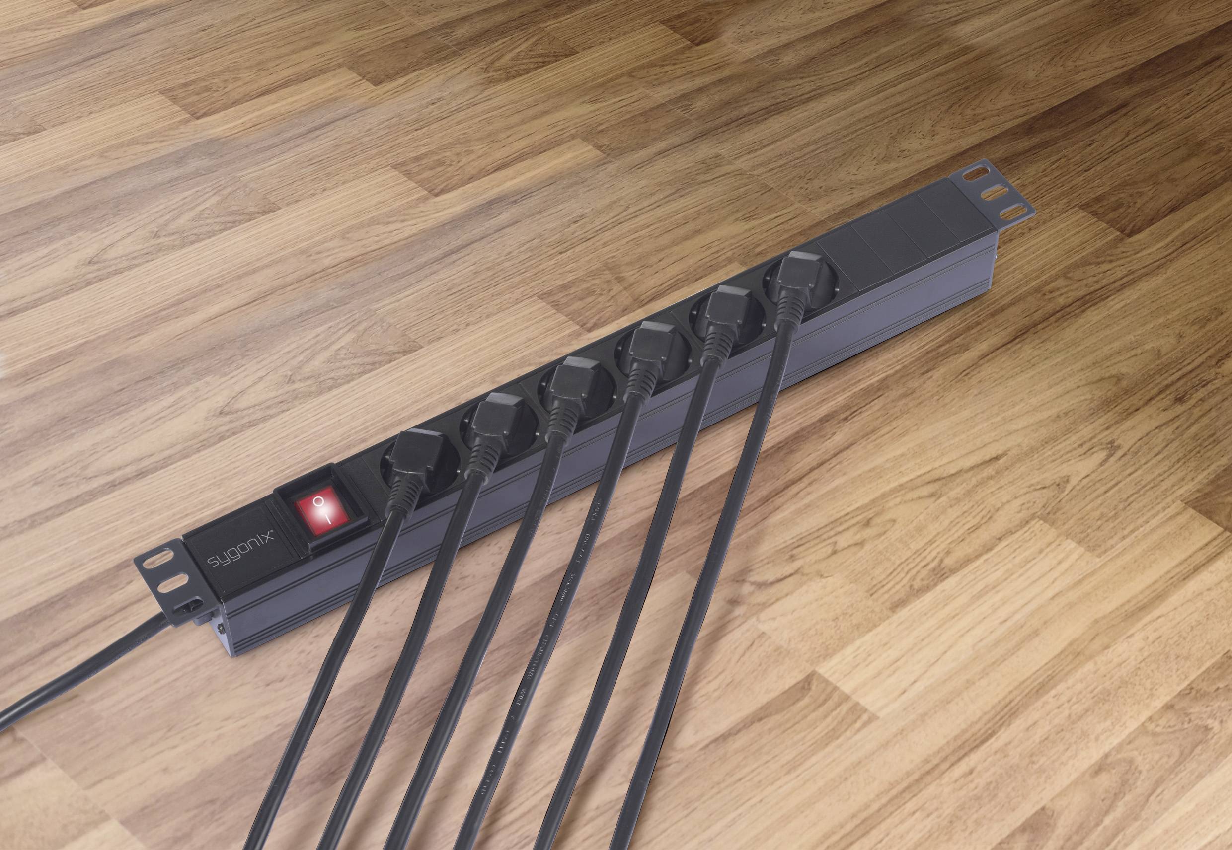 Mehrfachsteckdosenleiste mit sechs belegten Steckplätzen auf Holzfußboden, roter Schalter ist eingeschaltet.