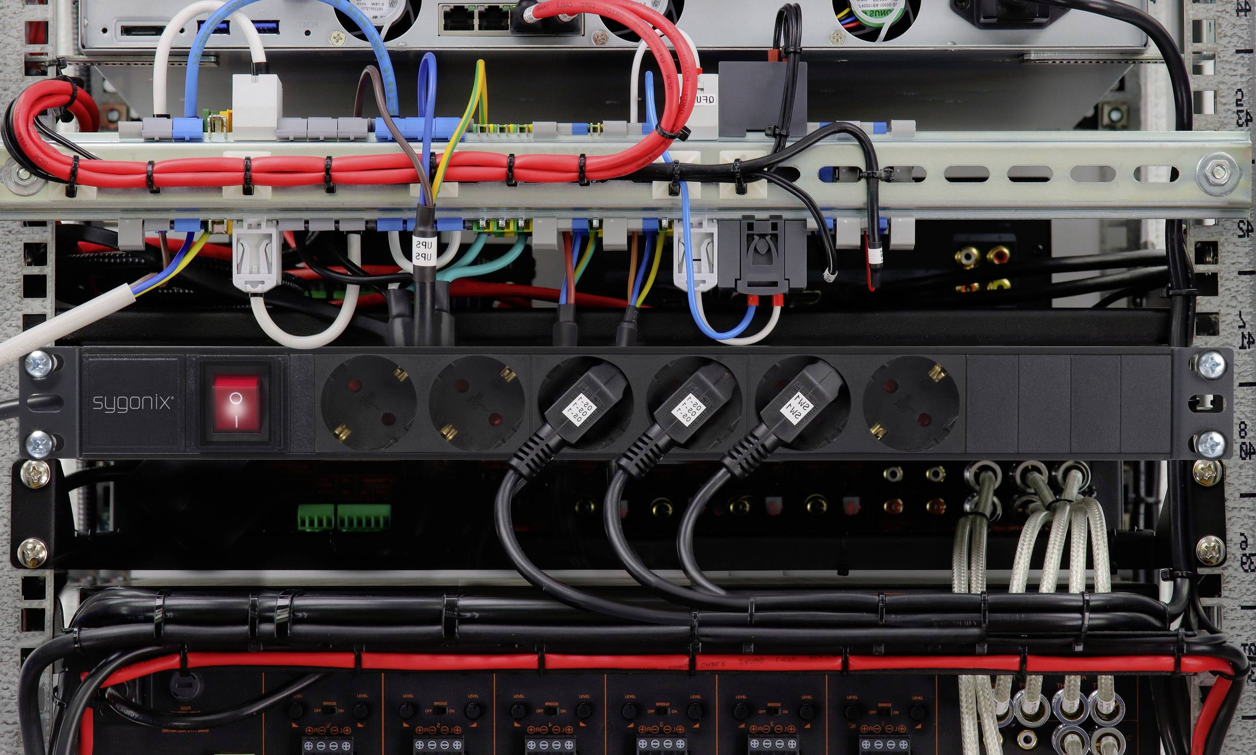 Ein offener Schaltschrank zeigt mehrere Kabel und angeschlossene Geräte. Verschiedene Stromleitungen und Verteilungen sind sichtbar.