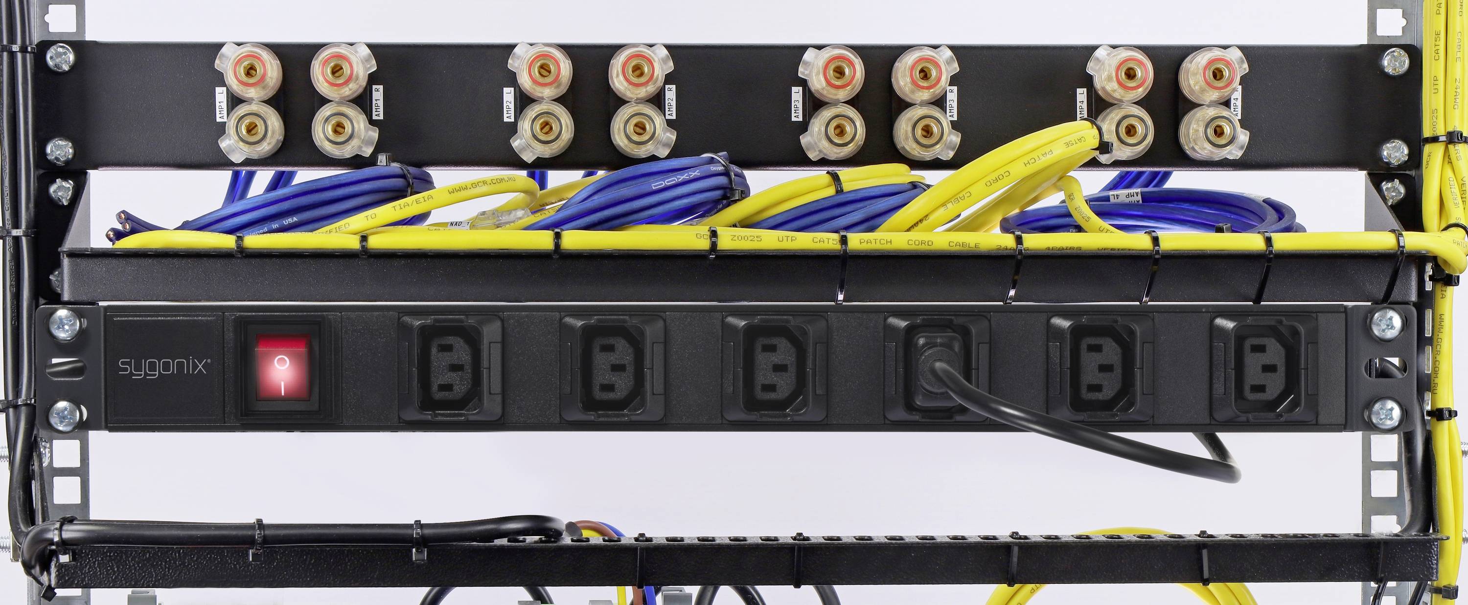 Ein Rack mit Audiobuchsen oben, darunter blaue und gelbe Netzwerkkabel, die mit einer Steckerleiste verbunden sind.