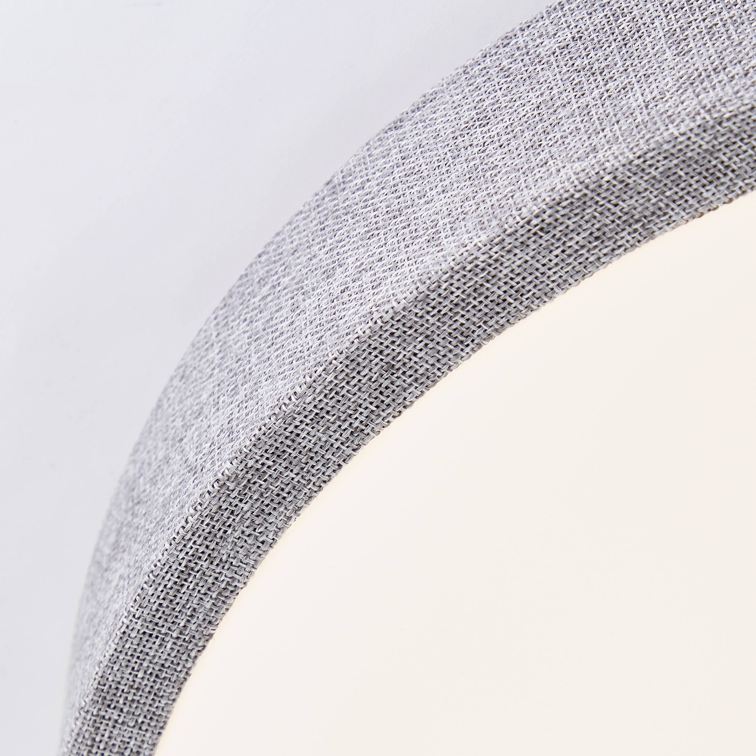 Ein Wand- oder Deckenleuchte mit rundem Stoffschirm, hell leuchtend auf weißem Hintergrund. Modernes, minimalistisches Design.