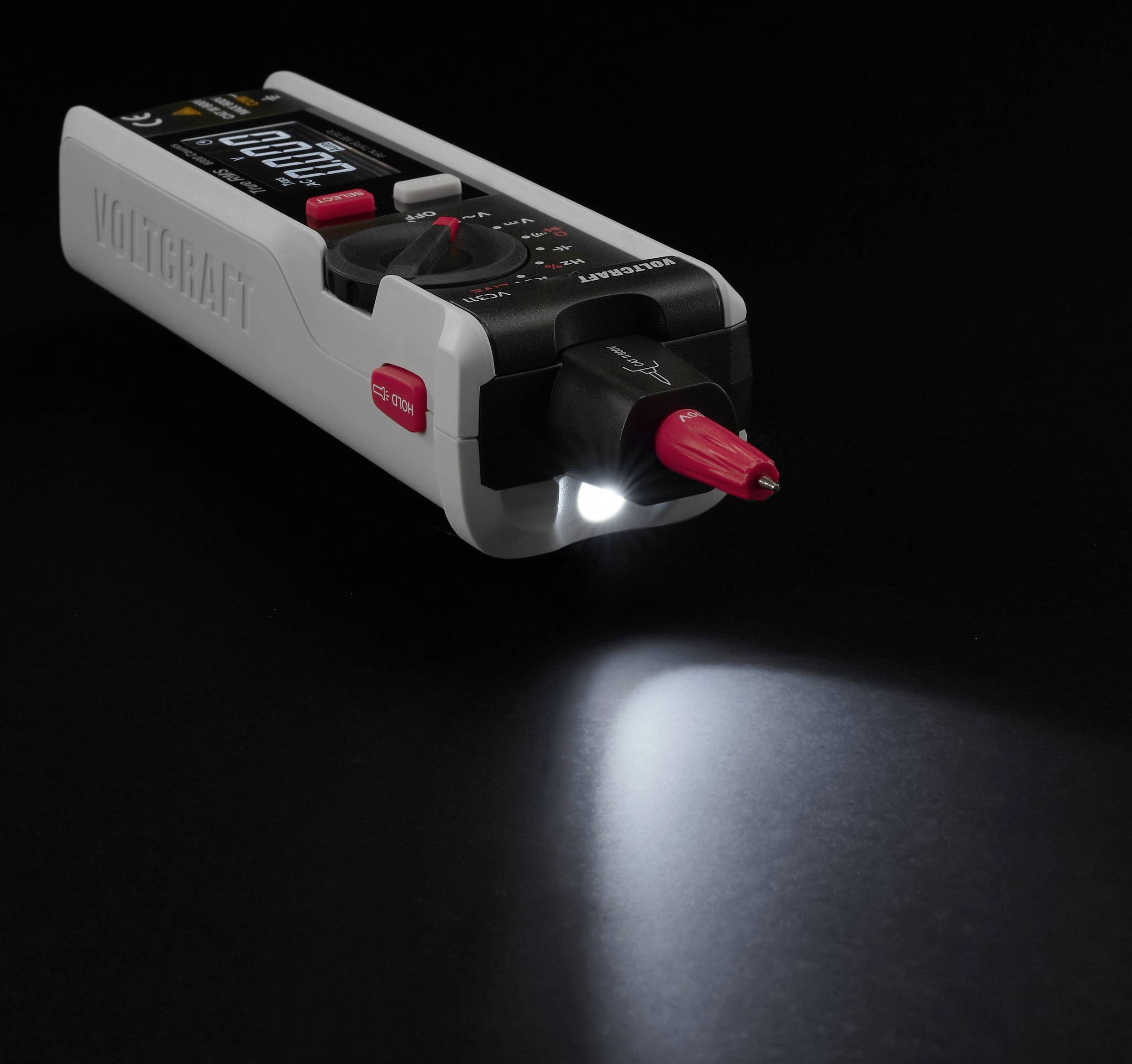 Ein digitales Multimeter liegt auf einer schwarzen Oberfläche und verfügt über eine beleuchtete LED-Taschenlampe und ein sichtbares Display.