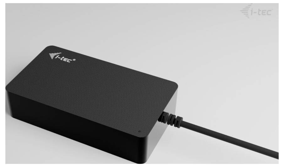 Schwarzes Netzteil von i-tec, liegend auf einer hellen Oberfläche, angeschlossenes Kabel auf der rechten Seite.