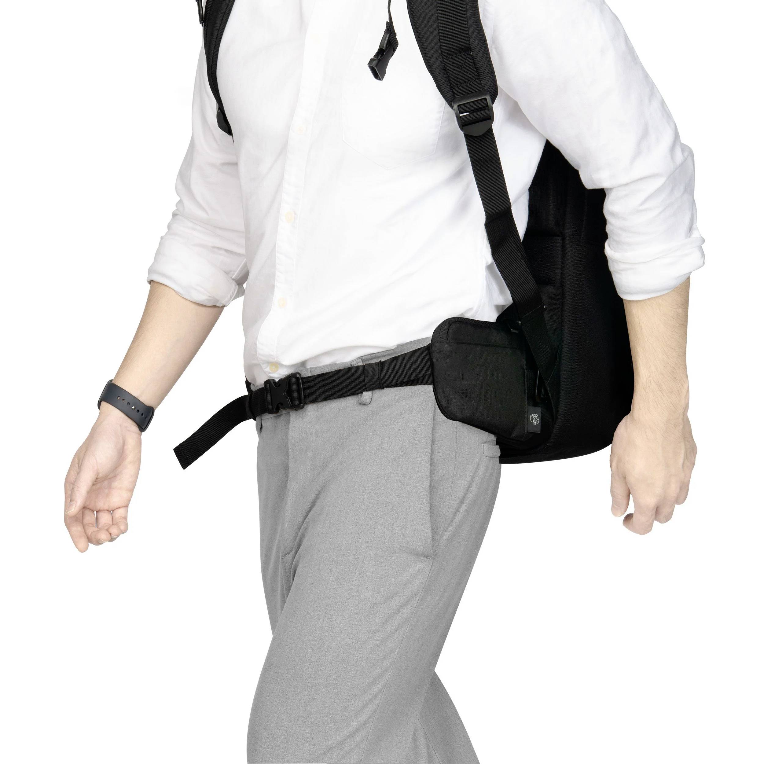 Mann in weißem Hemd und grauer Hose trägt einen Rucksack und eine schwarze Gürteltasche, geht zügig mit gesenktem Kopf.