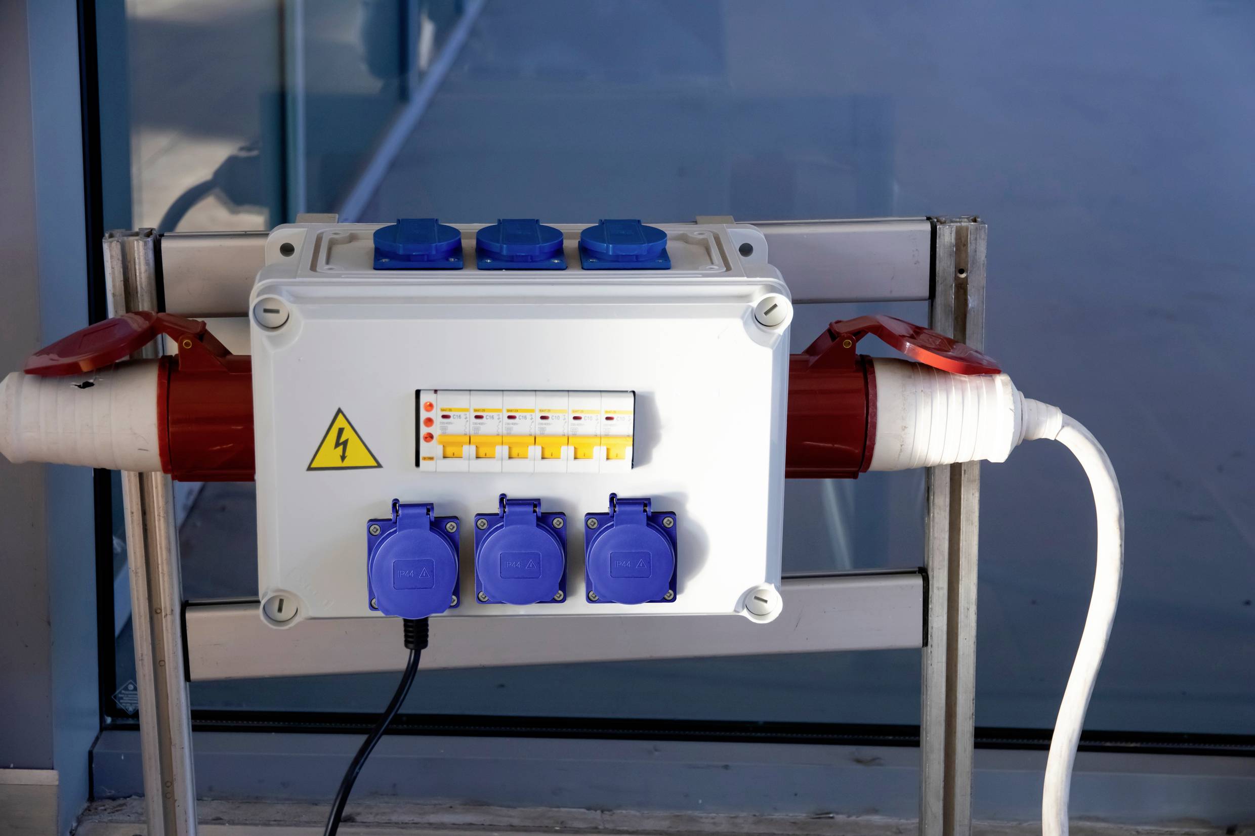 Stromverteilerkasten mit mehreren Steckdosen, Schaltern und Schutzabdeckungen, montiert an einer Metallwand.