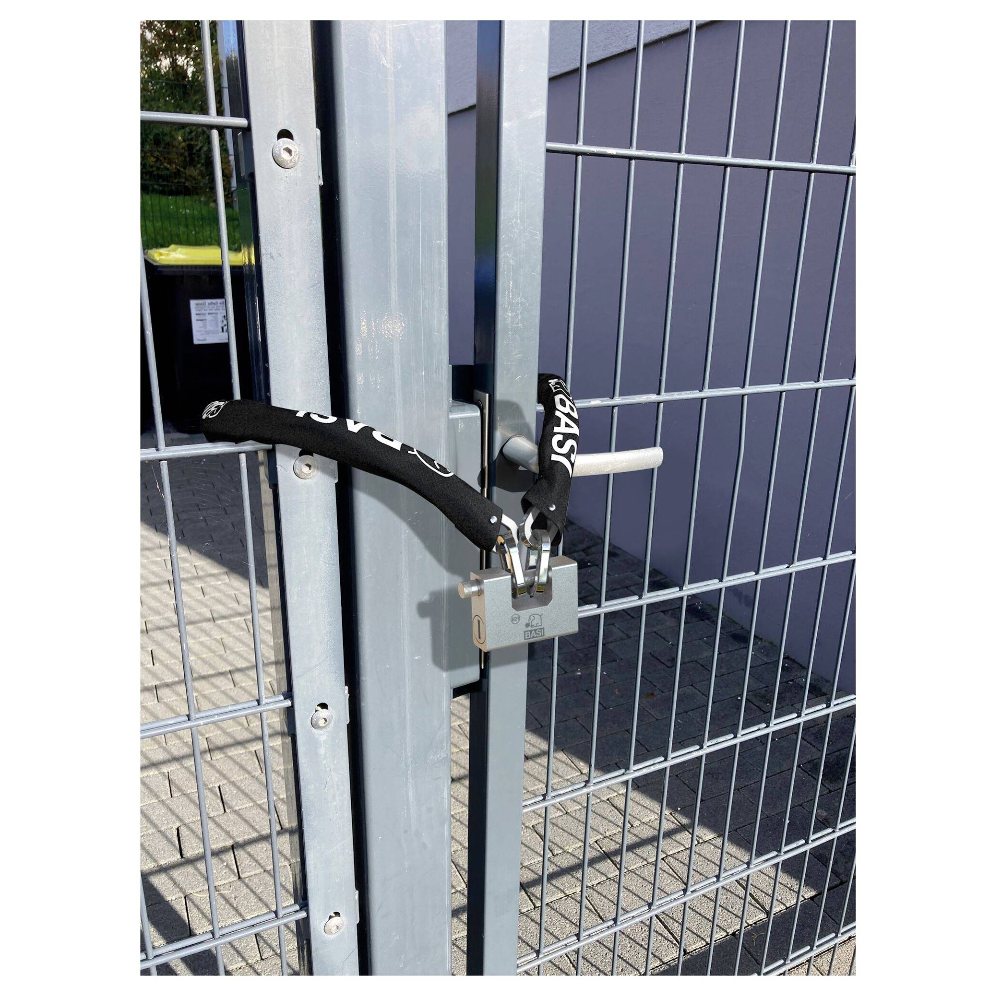 Ein verschlossenes Metalltor mit einem Vorhängeschloss und einem schwarzen Kabelschloss, das die Sicherheit betont.