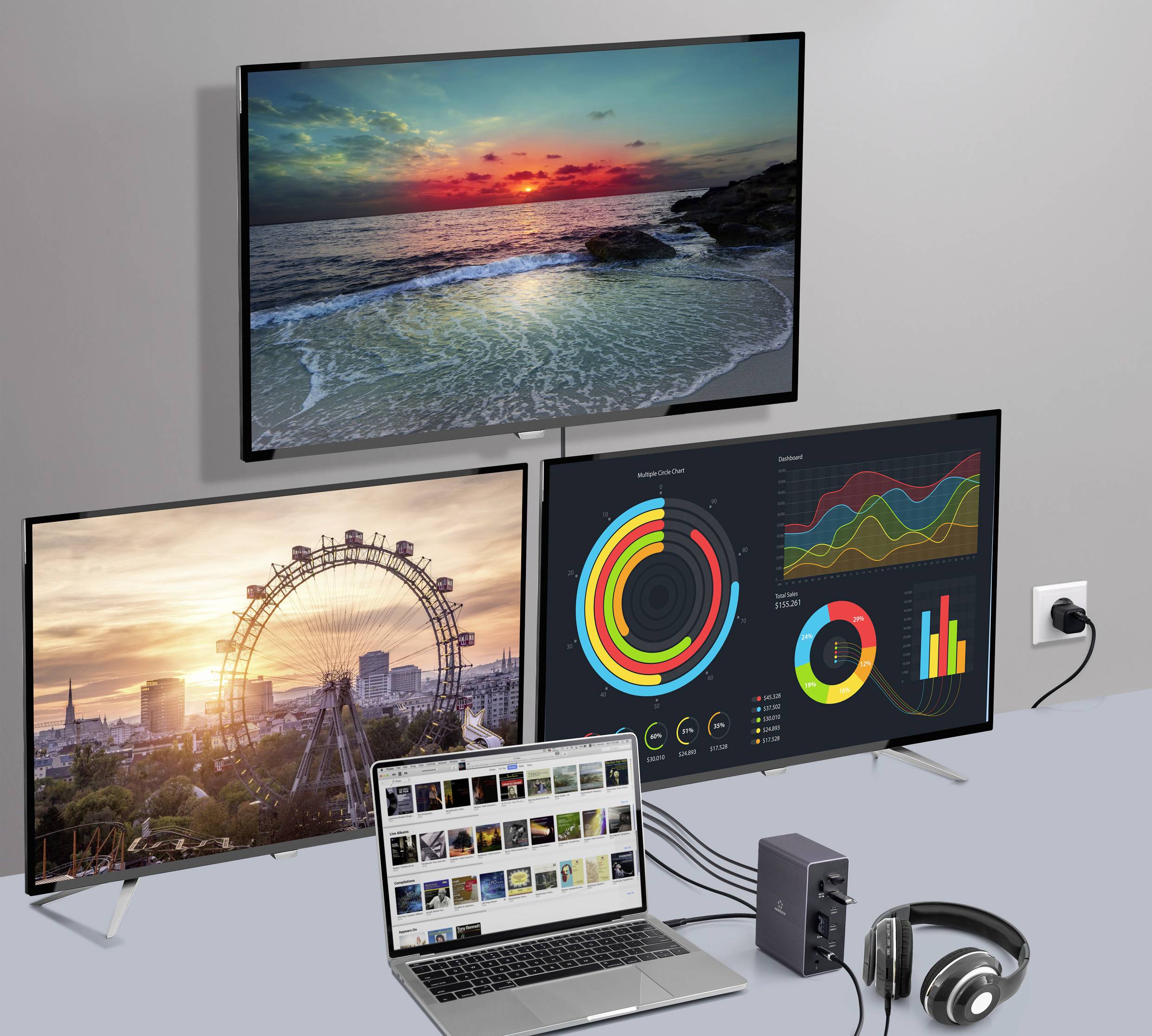 Ein Laptop ist an drei Monitore angeschlossen, die Videos, Landschaftsfotos und Diagramme zeigen; daneben steht ein Kopfhörer.