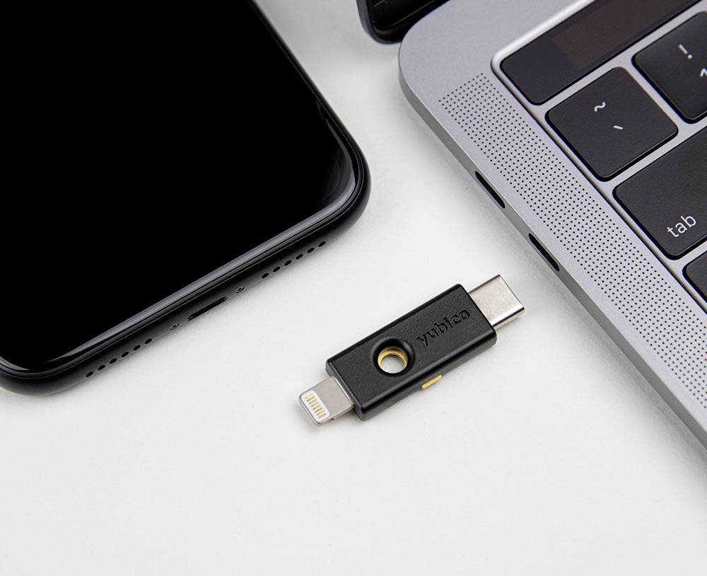 Ein USB-Stick liegt zwischen einem Smartphone und einem Laptop. Der Stick hat Anschlüsse für z.B. Lightning und USB-C.