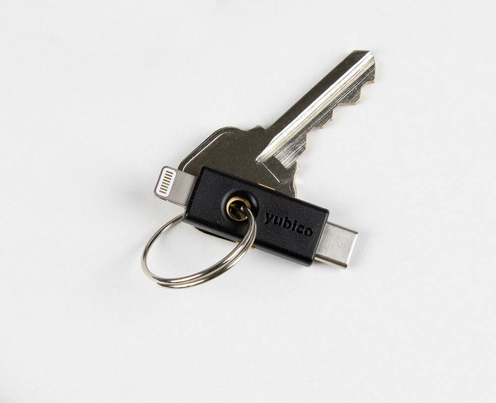 Ein USB-C-Sicherheitsstick und ein Schlüssel an einem Schlüsselring liegen auf einer weißen Oberfläche.