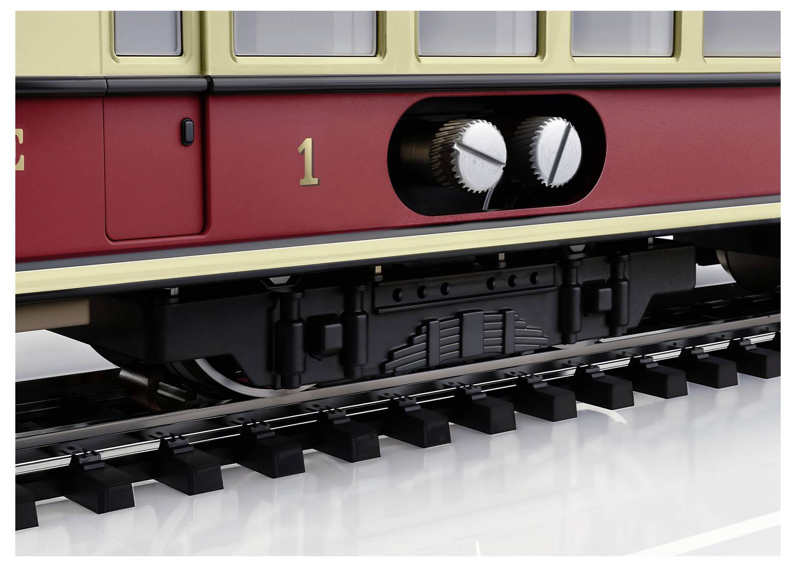 Nahaufnahme eines roten Zuges mit Zahnrädern an der Seite, die Räder sind auf Schienen. Es zeigt einen historischen Waggondesign-Detail.