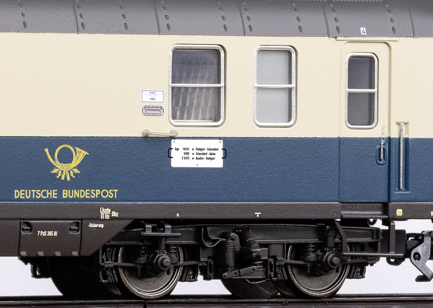 Ein Modell eines deutschen Postzugs in blau-beige, mit 'Deutsche Bundespost'-Logo auf der Seite, zeigt ein detailliertes Fahrwerk.