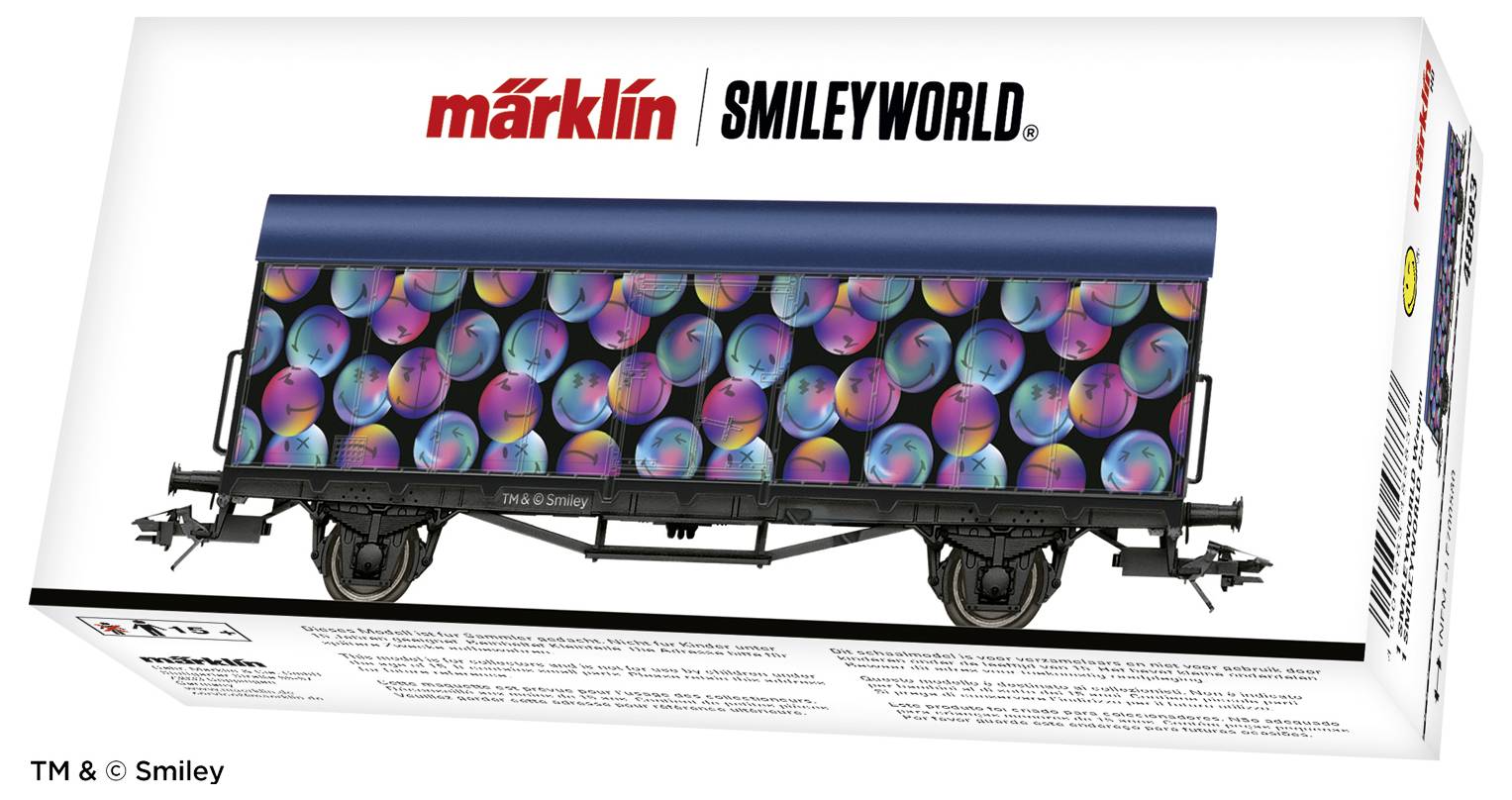 Eine Märklin-Modellbahnverpackung zeigt einen Güterwagen mit buntem Smiley-Muster. Markennamen oben, Produktdetails unten.