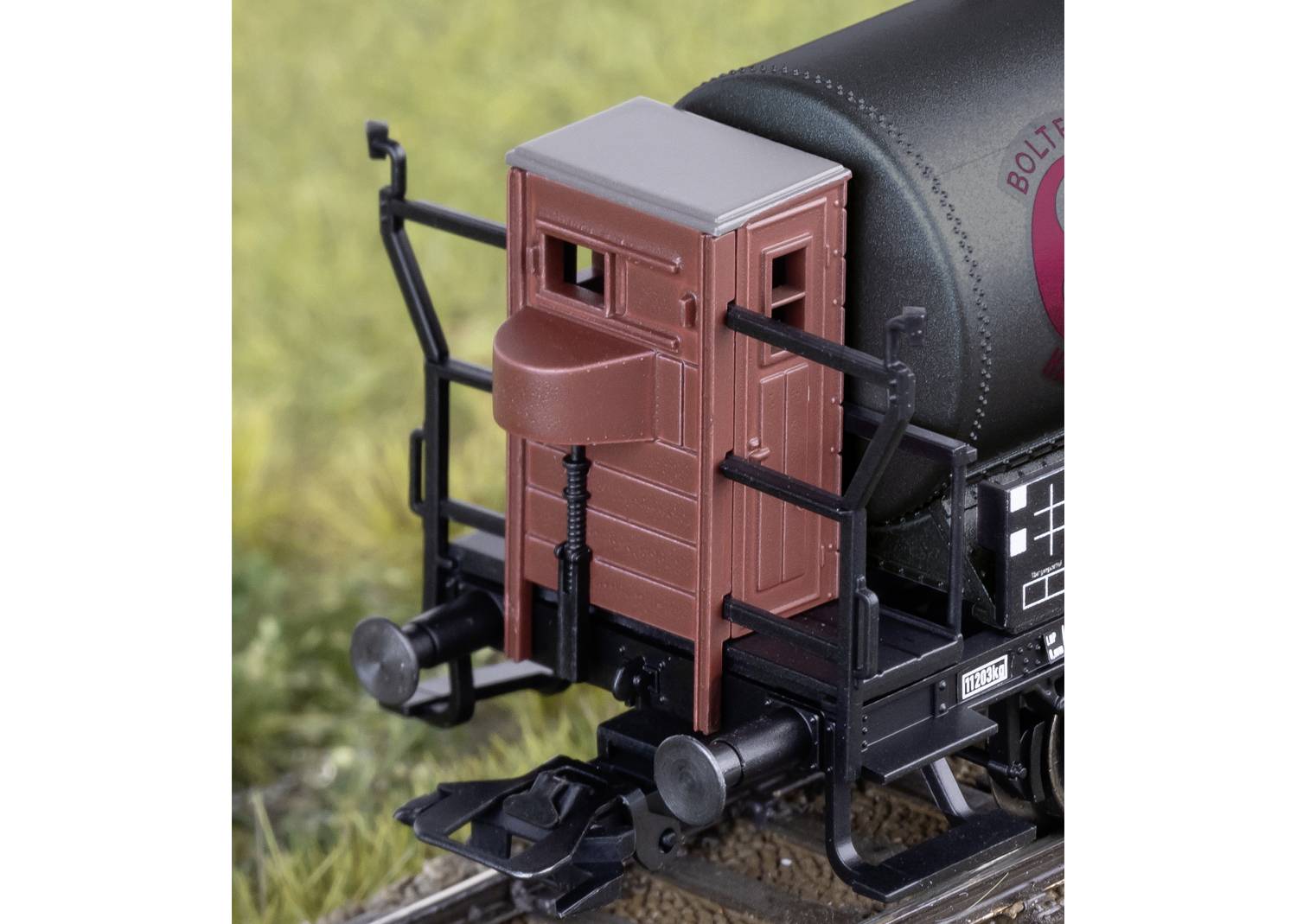 Ein Modell einer Zugkupplung mit einem rotbraunen Bremserhaus, umliegendem Gelände und Schienen in einer Detailaufnahme.