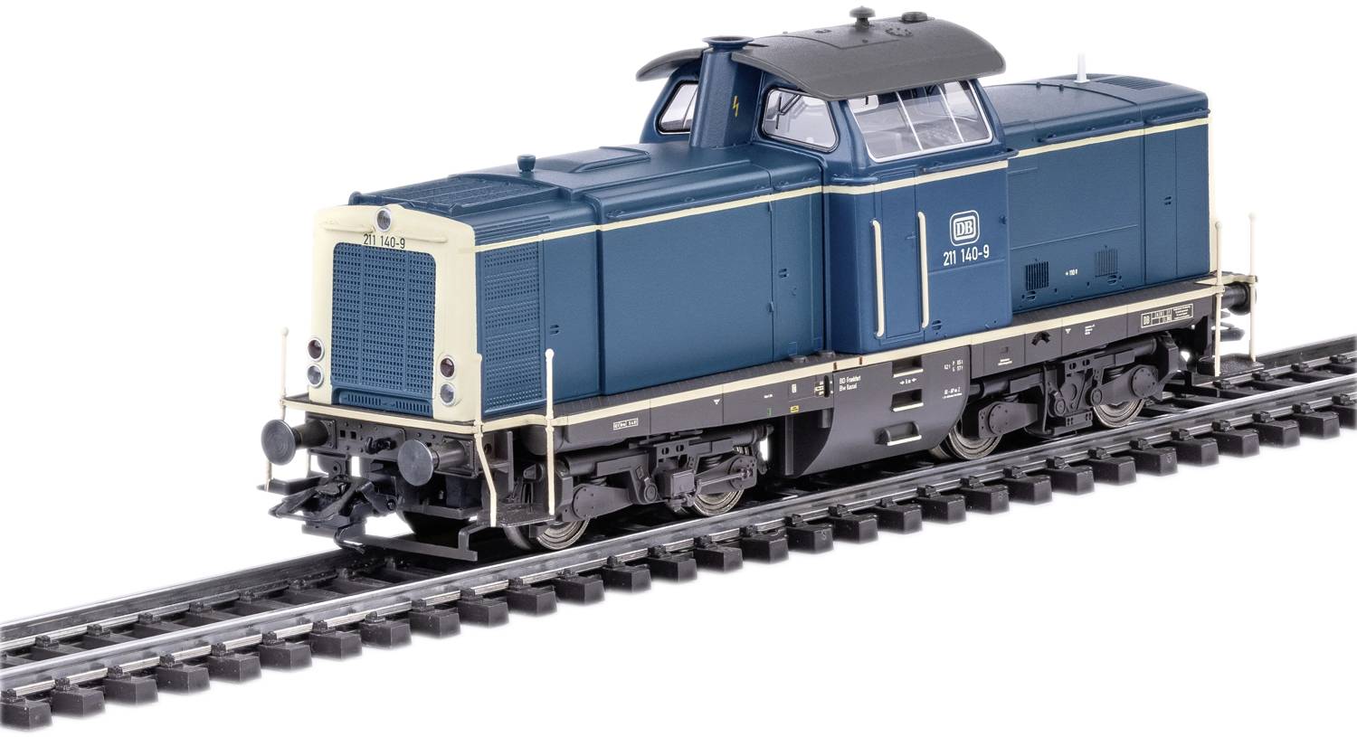 Ein Modellzug einer Diesellokomotive im Maßstab H0, blau lackiert mit weißen und schwarzen Details, fährt auf Schienen.