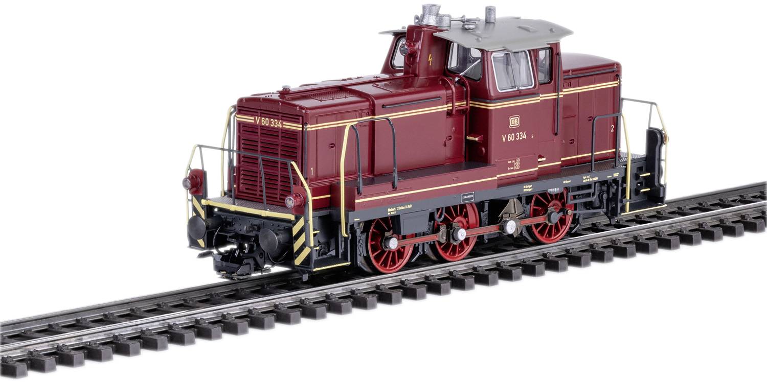 Eine rot-braune Modelllokomotive steht auf einem Gleis. Sie hat sechs Räder und gelbe Sicherheitsstreifen an den Seiten.