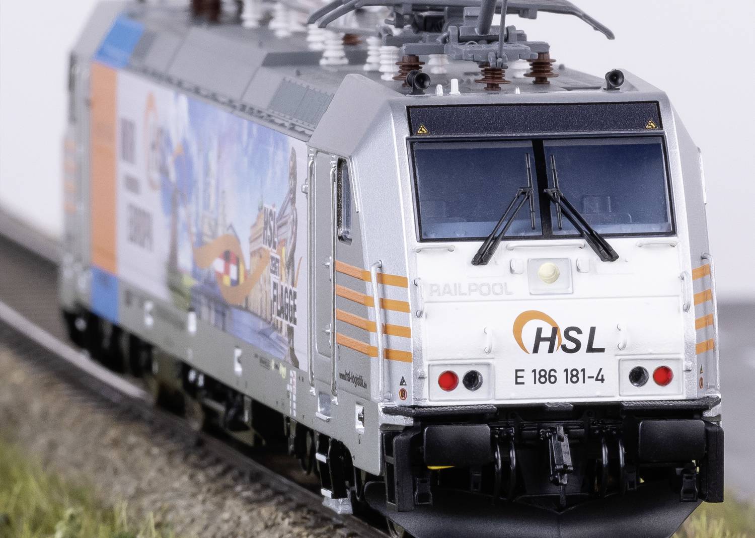 Modelleisenbahnlokomotive mit 'HSL'-Logo auf kurvigem Gleis, umlaufendes Werbedesign und detaillierter Aufbau.