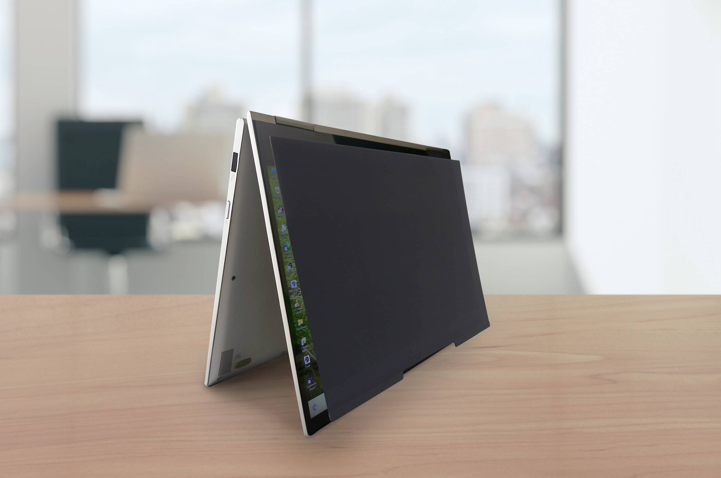 Ein auf einem Tisch stehendes, im Zeltmodus aufgestelltes Convertible-Laptop vor einem hellen Bürohintergrund.