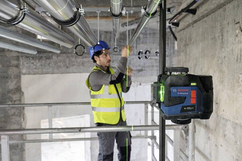 Ein Bauarbeiter mit Schutzhelm und Warnweste richtet in einem Gebäude mithilfe eines Bosch-Lasers Nivellierrohre aus.