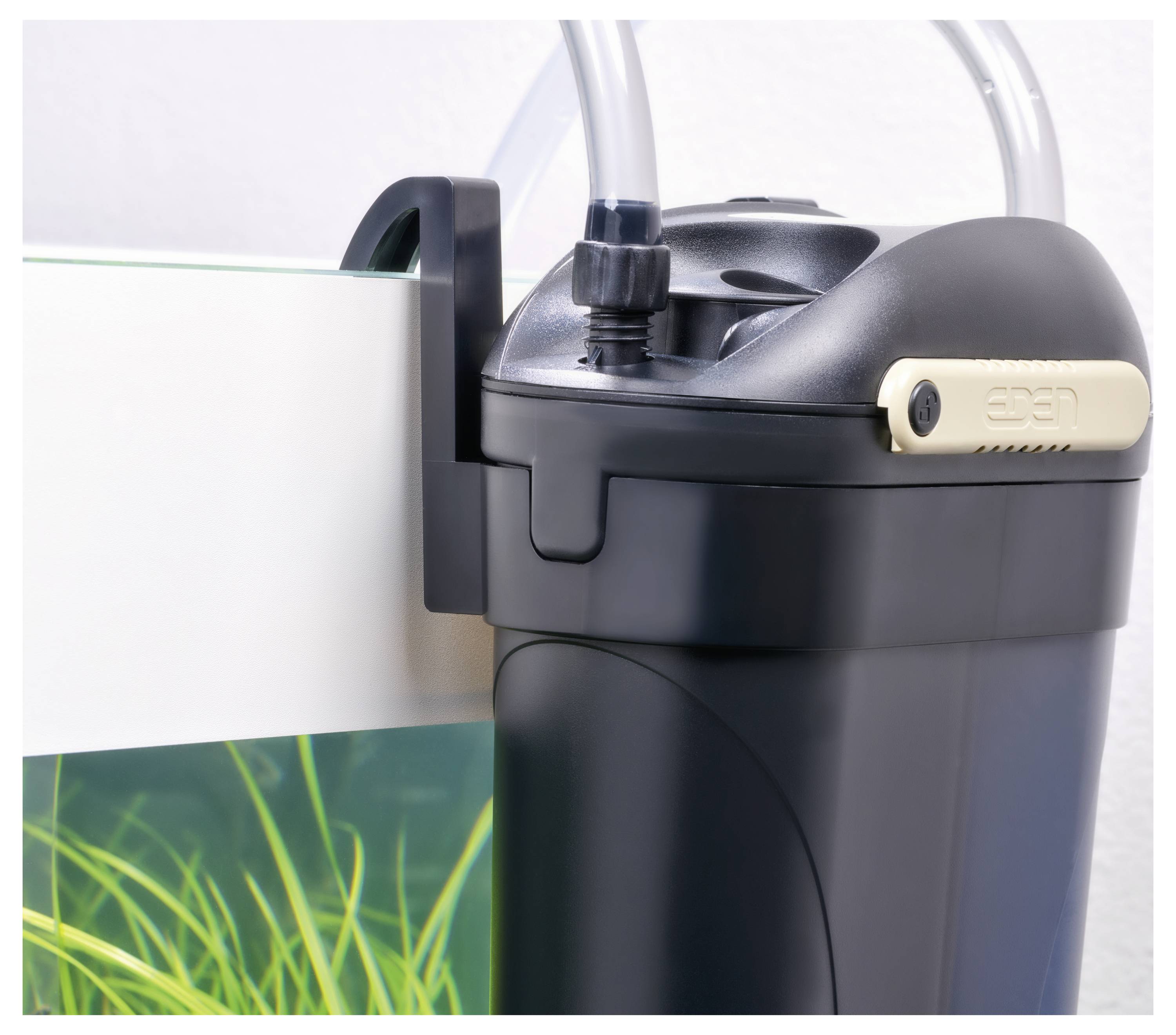 Ein schwarzer Kanisterfilter, der an der Seite eines Fischtanks befestigt ist, mit Schläuchen zur Wasserfilterung. Klares Wasser mit grünen Pflanzen im Inneren des Aquariums.