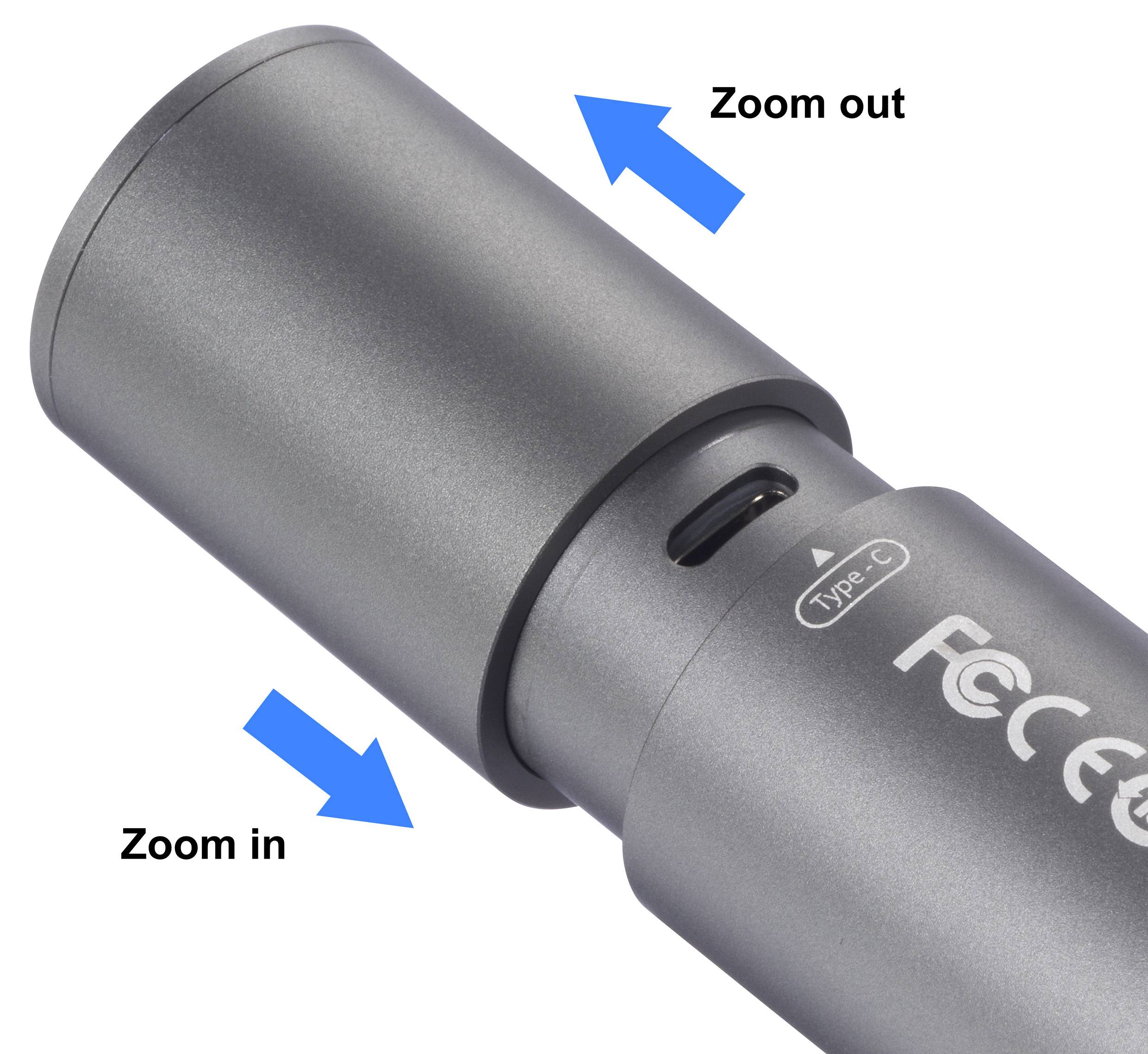 Silbernes zylindrisches Gerät mit Zoomfunktion, markiert durch blaue Pfeile: 'Zoom in' und 'Zoom out'.