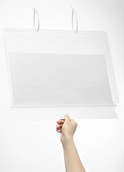 Eine Hand hält eine transparente Plastikmappe mit zwei weißen Haken oben, vor einem weißen Hintergrund.