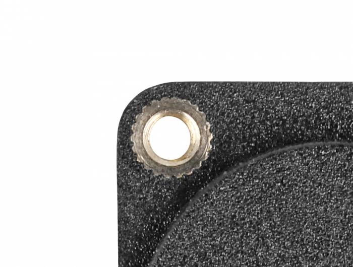 Detailaufnahme einer schwarzen, geriffelten Oberfläche mit einer Metallschraube in der oberen linken Ecke.