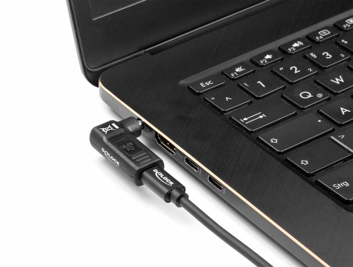 Ein schwarzes Laptop mit einem eingesteckten Ladekabel auf der linken Seite, Detailaufnahme der Tastatur und Anschlussport.