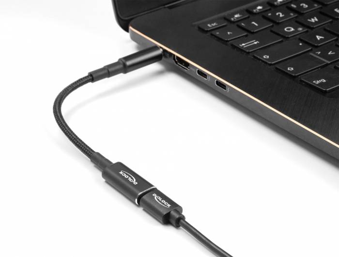 Ein USB-C-Kabel ist an einen Laptop angeschlossen und liegt auf einem weißen Tisch. Der Laptop zeigt die linke Seite mit USB-Anschlüssen.